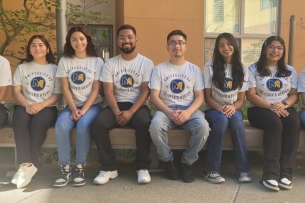 Fiat Lux scholars at UC Merced sit on a bench in a line.